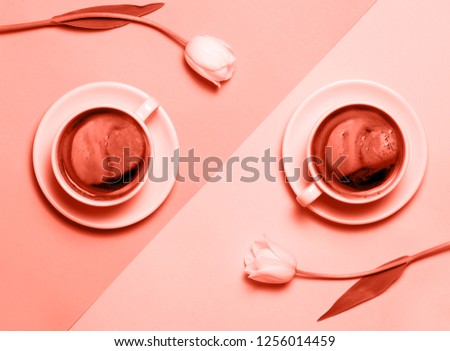 Flat lay of minimalistic picture of two cups of coffee and tulips colored in living coral. Trendy color of the year 2019. Minimalism coffee concept.