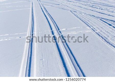 Traces of cars on white snow as a background .