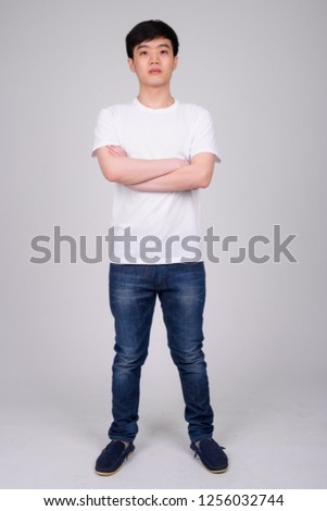 Full body shot of young Asian man standing with arms crossed