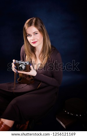 Portrait of beautiful woman holding retro photo camera on a dark blue background