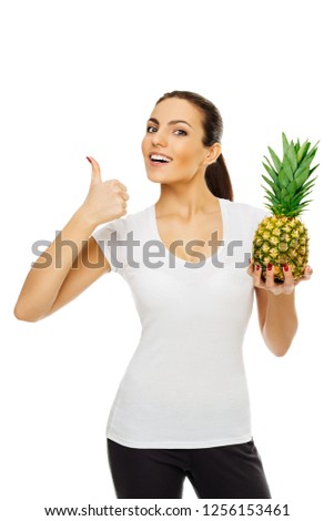 beautiful young happy brunette woman in white t-shirt holds pineapple. stands posing smiling on white background