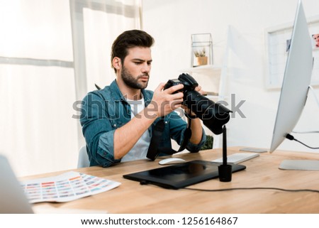 handsome professional young photographer using camera at workplace  