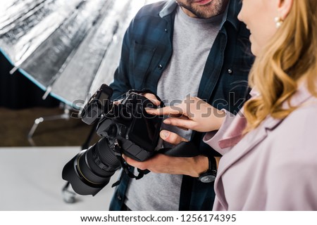 cropped shot of photographer and model using photo camera together