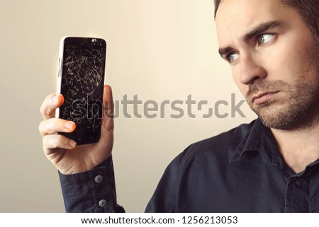 Young businessman with broken smartphone. a sad look. guy was upset about breaking his phone. Shattered phone display