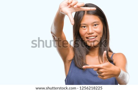 Young asian woman over isolated background smiling making frame with hands and fingers with happy face. Creativity and photography concept.