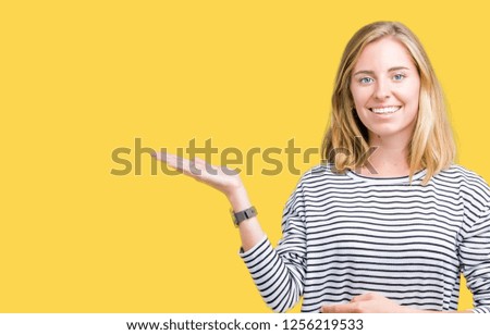 Beautiful young woman wearing stripes sweater over isolated background smiling cheerful presenting and pointing with palm of hand looking at the camera.
