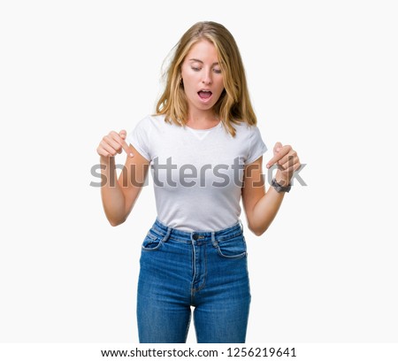Beautiful young woman wearing casual white t-shirt over isolated background Pointing down with fingers showing advertisement, surprised face and open mouth