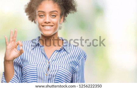 Young afro american woman over isolated background smiling positive doing ok sign with hand and fingers. Successful expression.