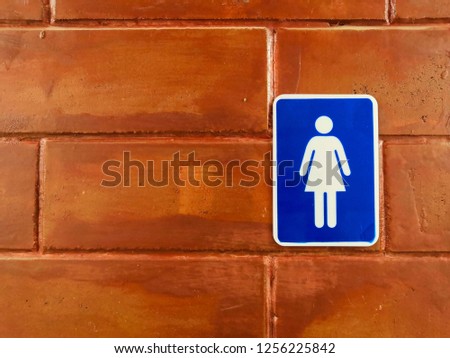 Woman bathroom sign on brown tile wall.Female toilet sign.