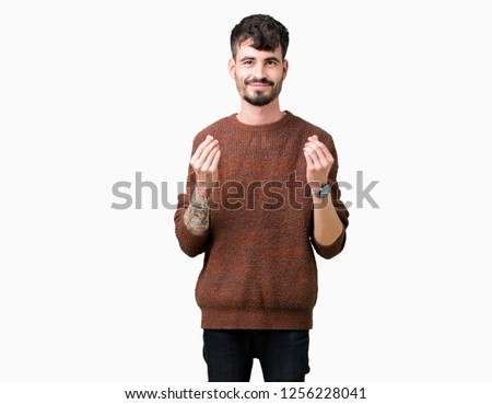 Young handsome man wearing winter sweater over isolated background Doing money gesture with hand, asking for salary payment, millionaire business