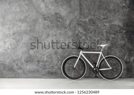 White bike on grey concrete wall, real photo with copy space