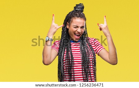 Young braided hair african american girl over isolated background shouting with crazy expression doing rock symbol with hands up. Music star. Heavy concept.