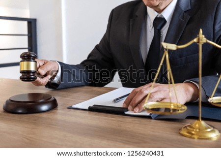 Legal law, advice and justice concept, counselor lawyer or notary working on a documents and report of the important case and wooden gavel, brass scale on table in courtroom.