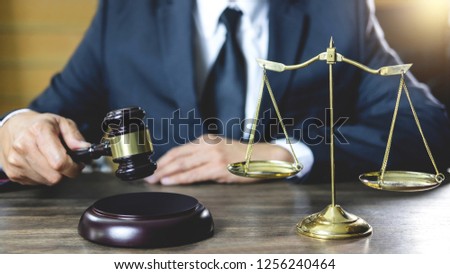 Legal law, advice and justice concept, male lawyer or notary working on a documents and report of the important case and wooden gavel, balance on table in courtroom.