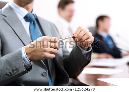 businessman sitting at a table and holding a pen Royalty-Free Stock Photo #125624279