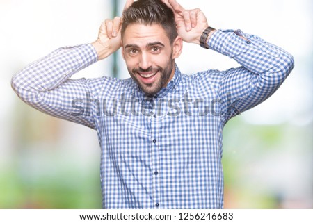 Young handsome man over isolated background Posing funny and crazy with fingers on head as bunny ears, smiling cheerful