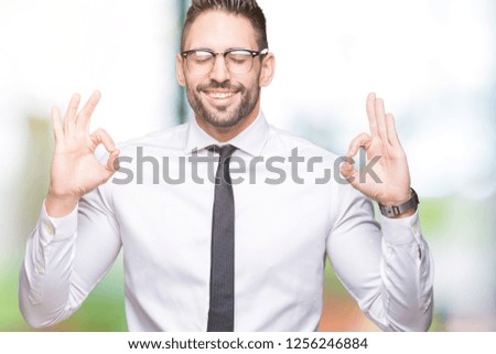 Young handsome business man wearing glasses over isolated background relax and smiling with eyes closed doing meditation gesture with fingers. Yoga concept.