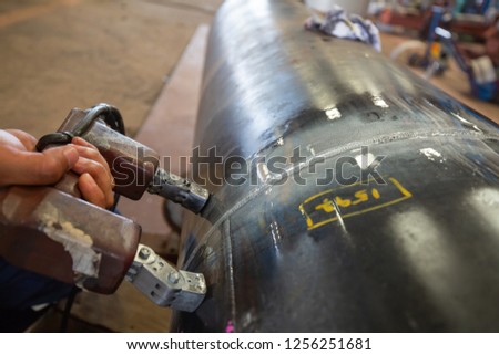 Male worker test steel pipeline butt weld carbon background white contrast of magnetic field test