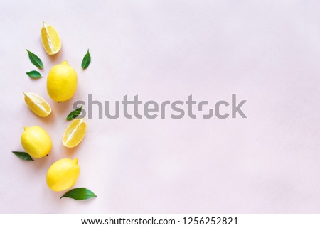 Lemons with green leaves on pink pastel background, top view, copy space. Organic fresh citrus fruits lemons, minimal conceptual flat lay.
