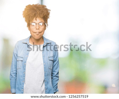 Beautiful young african american woman wearing glasses over isolated background making fish face with lips, crazy and comical gesture. Funny expression.