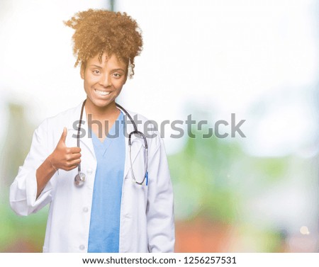 Young african american doctor woman over isolated background doing happy thumbs up gesture with hand. Approving expression looking at the camera with showing success.