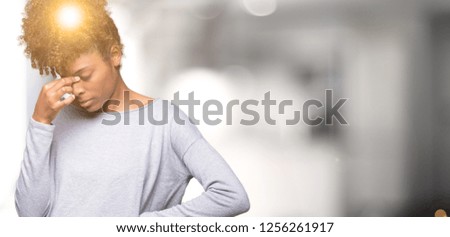 Beautiful young african american woman over isolated background tired rubbing nose and eyes feeling fatigue and headache. Stress and frustration concept.