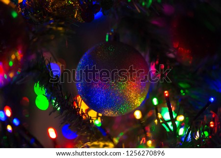 Magical rainbow Christmas ball hanging on a Christmas tree. Christmas lights make the silver shiny ball colorful and rainbow. New Year, Christmas, festive background. Happy holidays!