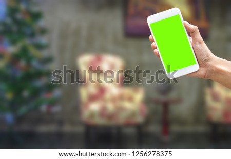 A man hand holding a  green screen smartphone on left bottom  to use application to reserve hotel activity on new year chrismas eve 2019 - can use a phone apps with blurred background