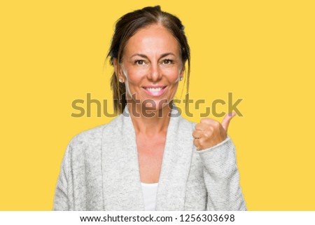 Beautiful middle age adult woman wearing winter sweater over isolated background doing happy thumbs up gesture with hand. Approving expression looking at the camera with showing success.