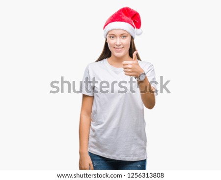 Young beautiful caucasian woman wearing christmas hat over isolated background doing happy thumbs up gesture with hand. Approving expression looking at the camera with showing success.