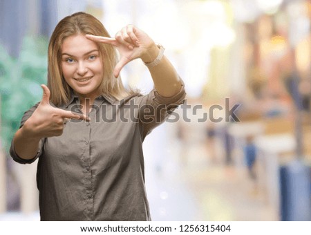 Young caucasian business woman over isolated background smiling making frame with hands and fingers with happy face. Creativity and photography concept.