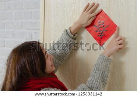 Young asian woman pastes spring couplet. It is the tradition of Chinese culture to stick spring couplet to the doors for Chinese New Year. The word on the spring couplet means "spring is coming" Royalty-Free Stock Photo #1256331142