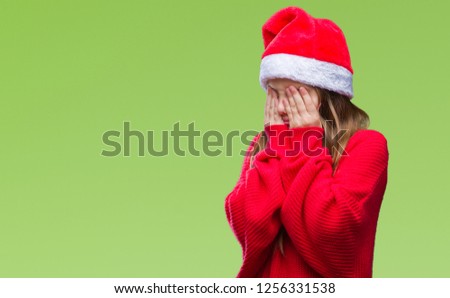 Young beautiful girl wearing christmas hat over isolated background with sad expression covering face with hands while crying. Depression concept.