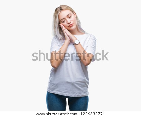 Young blonde woman over isolated background sleeping tired dreaming and posing with hands together while smiling with closed eyes.