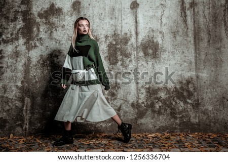 Posing in sweater. Blonde-haired slim trendy photo model posing in warm sweater and waist bag Royalty-Free Stock Photo #1256336704