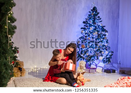 mother and little boy open Gifts Christmas tree new year