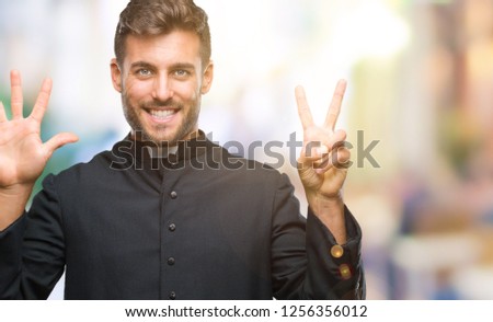 Young catholic christian priest man over isolated background showing and pointing up with fingers number seven while smiling confident and happy.
