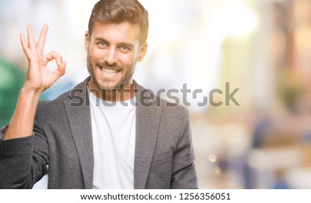 Young handsome business man over isolated background smiling positive doing ok sign with hand and fingers. Successful expression.