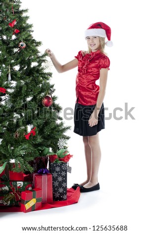 Cute pre adolescent girl touching Christmas tree over white background