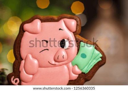 Holiday traditional food bakery. Gingerbread lucky pink pig with bundle of money in cozy warm decoration with garland lights.