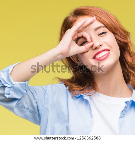 Young beautiful business woman over isolated background doing ok gesture with hand smiling, eye looking through fingers with happy face.