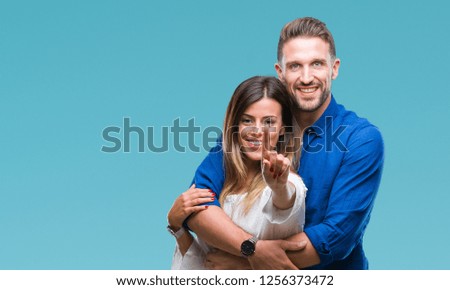 Young couple in love over isolated background showing and pointing up with finger number one while smiling confident and happy.