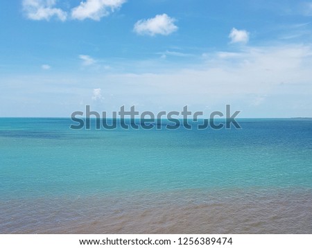 Aerial view of beautiful ocean shoal landscape with colorful azure, green, brown and blue water near Caribbean coral atoll island, sunny weather, clear sky with clouds in the background