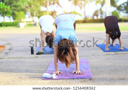 Close up Woman and women in background doing or practice the yoga in public parks at the morning with sunrise. Sports and healthy concept.
