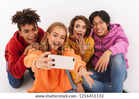 Group of cheerful teenagers isolated over white background, taking a selfie