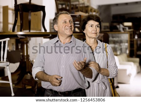 Portrait of cheerful mature woman with her husband who are satisfied of buying furniture in antique store