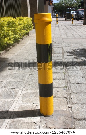 Red and yellow metal post along the sidewalk. The fence between the pedestrian zone and the highway. limited parking area. protection from a terrorist act, from death cars going to ram.