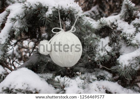 New Year or Christmas white textile knited ball hangs on natural christmas tree background. Can be used as wallpaper or greeting card. Selective focus. 