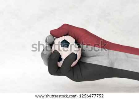 Mini ball of football in Yemen flag painted hand on white background. Concept of sport or the game in handle or minor matter. a horizontal tricolour of red, white and black.