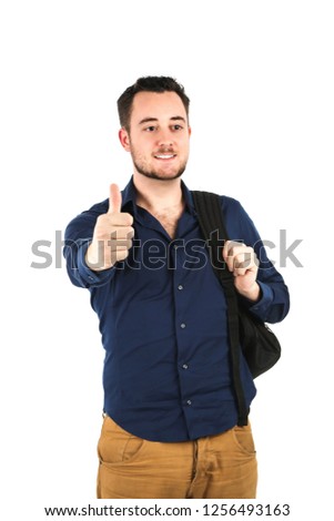 Happy young male student doing a thumb up gesture with his hand while wearing a backpack against a white background